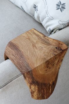 a wooden table sitting on top of a gray couch next to pillows and pillow cases