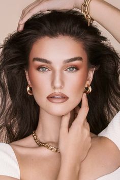 a woman wearing gold jewelry and posing for a magazine cover photo with her hands on her head