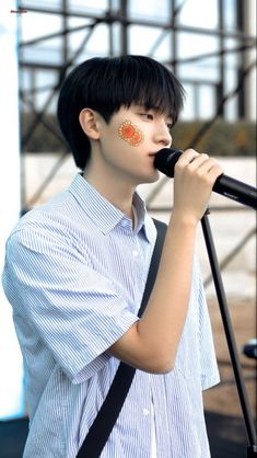 a young man holding a microphone up to his mouth while standing in front of a stage