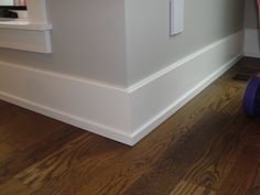 there is a purple toy sitting on the floor in front of a white wall and wooden floors