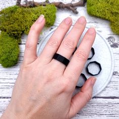 a person's hand with a black ring on top of a white and gray plate