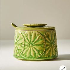 a green canister with a wooden spoon in the top and lid on it's side