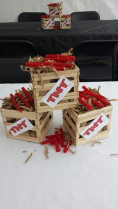 four wooden crates with red peppers in them sitting on a white tablecloth covered table