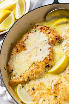 a pan filled with chicken and lemons on top of a white cloth next to sliced lemons