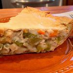 a slice of chicken pot pie on an orange plate