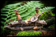 three figurines sitting on top of a log in the woods