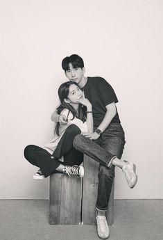 black and white photograph of two people sitting on top of a wooden box with their arms around each other