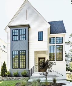 a large white house with lots of windows on it's side and stairs leading up to the front door