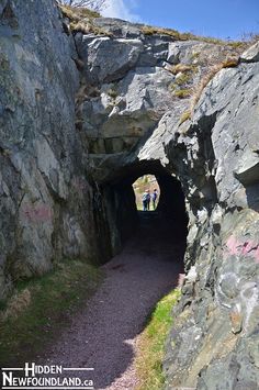 two people are walking through a tunnel in the rocks