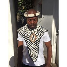 Immerse yourself in the rich heritage of the Zulu culture with our exquisite Zulu Mbata (warrior chestguard) made of cotton fabric with patterns of a zebra, Umgexo (Beaded necklace made of fake animal teeth)  and Umqhele (traditional headband) set made of real zebra skin and cow tail, meticulously handcrafted from genuine zebra skin, cow skin, beads and cotton fabrics. This stunning set is a true embodiment of Zulu craftsmanship and is perfect for collectors, cultural enthusiasts, or anyone looking to add a touch of African tradition to their space. Key Features: Authentic Craftsmanship: Each piece is handmade by skilled artisans from South Africa, ensuring authenticity and exceptional quality. Real Zebra Skin: The headband is made from genuine zebra and cowskin, this set offers a unique a White Habesha Kemis For Traditional Ceremonies, White Habesha Kemis For Ceremonial Festivals, White Habesha Kemis With Traditional Patterns For Ceremonies, Traditional White Habesha Kemis For Festival, Zulu Traditional Attire For Men, Zulu Culture, Cow Tail, Zulu Traditional Attire, Shaka Zulu