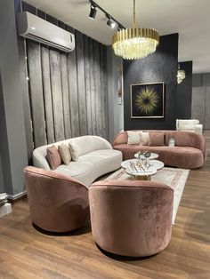 a living room filled with furniture and a chandelier hanging above the couches