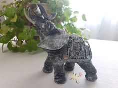 an elephant figurine sitting on top of a table next to a potted plant