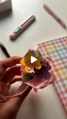 a person is holding a paper flower in their hand