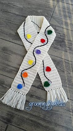 a white scarf with multicolored beads and tassels on the end is laying on a wooden floor