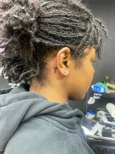 a woman with dreadlocks and ear piercings on her ears in a salon