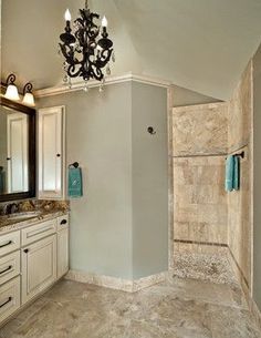 a large bathroom with a chandelier and marble counter tops on both sides of the shower