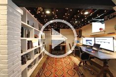 a room with a desk, computer monitor and bookshelves on the wall in front of it