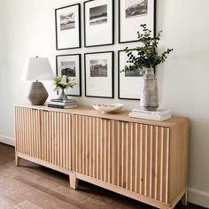 a wooden sideboard with pictures on the wall above it