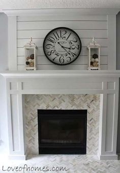 a white fireplace with a clock above it and candles on the mantel over the mantle