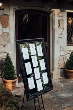 a sign with notes attached to it in front of a building and potted plants