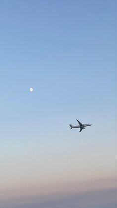 an airplane is flying in the sky with a half moon behind it and some clouds