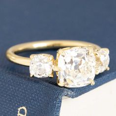 Trilogy rings are one of those design motifs that will never go out of style - representative of the past, future, and present with three chunky old mine cut diamonds in 18kt gold. We love this parcel for their super square shapes and matched faceting - not to mention that center stone with a face up much brighter than its’ graded color! These diamonds span beautifully across the finger and offer up so much chunk and diamond fire - obsessed is an understatement. 18kt yellow gold Size 6 & resizab Timeless Square Cut Rose Diamonds Jewelry, Timeless Square Cut Rose Cut Diamond Rings, Fine Jewelry Ring With Square Cut Rose Diamonds, Timeless Square Cut Diamond Ring With Rose Cut Diamonds, Timeless Square-cut Rose Diamond Ring, Timeless Square Cut Rose Diamond Ring, Three Stone Cushion Cut Ring, Timeless Square-cut Ring With Single Cut Diamonds, Timeless Square Cut Ring With Single Cut Diamonds