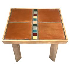 a wooden table with multicolored tiles on the top and bottom, against a white background