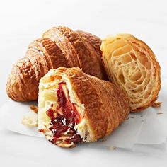 two croissants with jelly filling on white paper