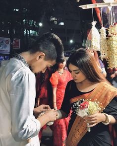 two people standing next to each other holding flowers