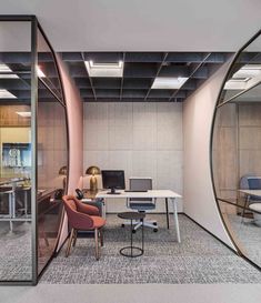 an office with glass walls and desks in the center, along with two chairs