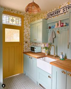 a kitchen with blue cabinets and yellow door, white sink and wooden countertop area