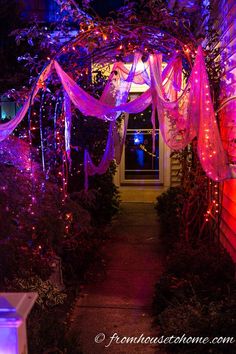 the entrance to a house is decorated with purple lights and pink sheer curtains over it