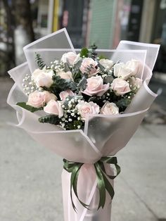 a bouquet of white roses tied to a pole on the sidewalk in front of a building