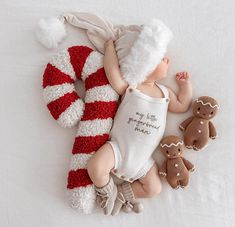 a baby is sleeping next to two gingerbread cookies and a teddy bear wearing a santa hat