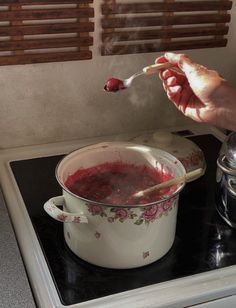 a person is stirring something in a pot on top of the stove with a spoon