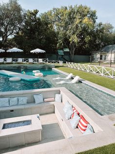 an outdoor swimming pool with lounge chairs and umbrellas on the grass next to it