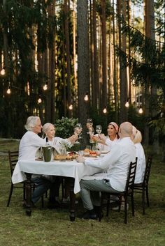 a group of people sitting around a table with food and wine glasses in their hands