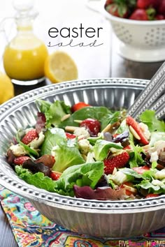 a salad in a bowl with strawberries on the side and lemons behind it