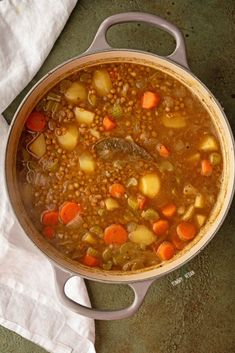 a pot filled with soup sitting on top of a table next to a white napkin