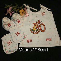 an embroidered bib, booties and baby bibs are laid out on a black surface