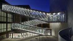 the building is lit up at night and has many glass stairs leading to different levels