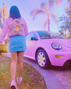 a woman walking past a pink car with donuts in it's back pocket