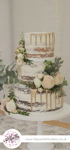 a three tiered cake with flowers and dripping icing on the top, sitting on a table