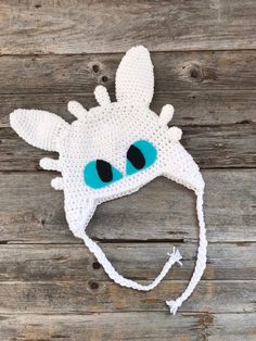 a crocheted giraffe hat with blue eyes on top of a wooden surface