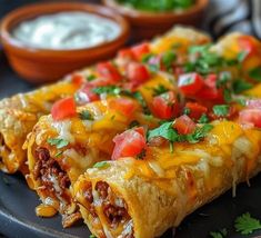 two burritos on a black plate with salsa and sour cream in the background