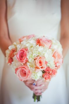 a bride holding a bouquet of pink and white flowers