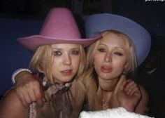 two beautiful young women wearing pink hats posing for a photo in front of a camera