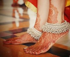 the legs and feet of a woman with henna tattoos on their feet are adorned with jewels