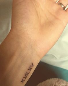 a woman's wrist tattoo with roman numerals on the left side of her hand