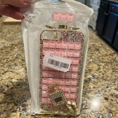 someone is holding up a pink phone case with gold chains and jewels on it in the kitchen